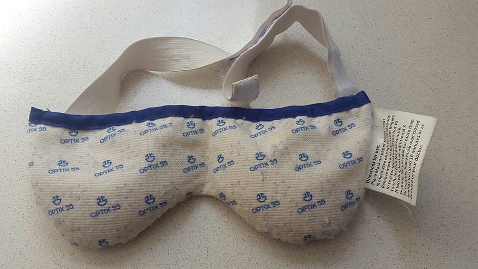 Microwavable warm compress mask used for eyelid therapy resting on a countertop.